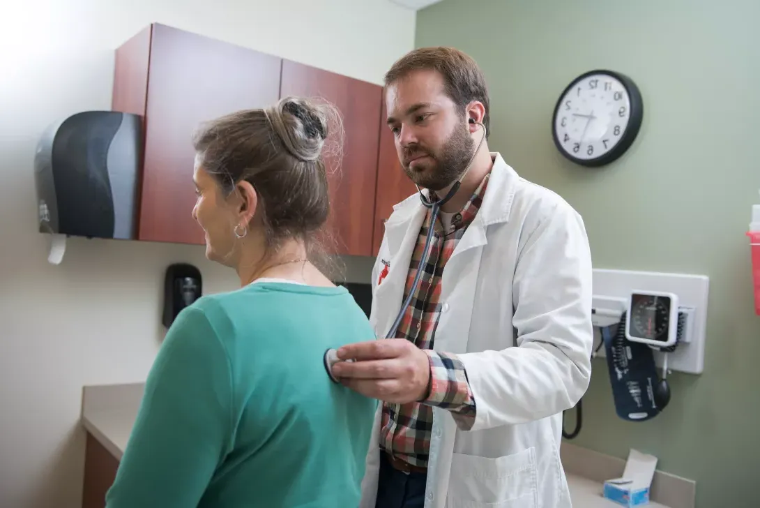 Male nursing student examines a female patient